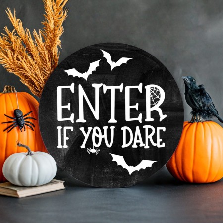 Black round sign decorated with white bats and the words Enter If You Dare