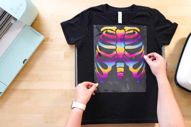 hands placing skeleton decal on pink shirt
