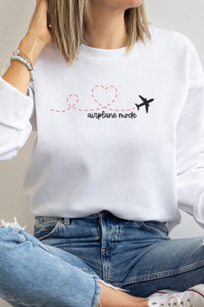 White sweatshirt on blonde woman. Sweatshirt says "airplane mode" with an airplane making a heart